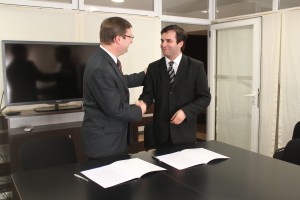 El Dr. Juan Carlos Mena y el Dr. Pablo Raúl Storni estrechando sus manos luego de haber suscripto el Convenio.